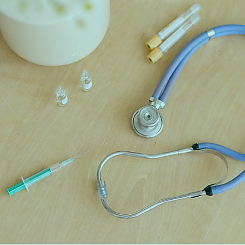 Medical stethoscope, syringe and vials on a table